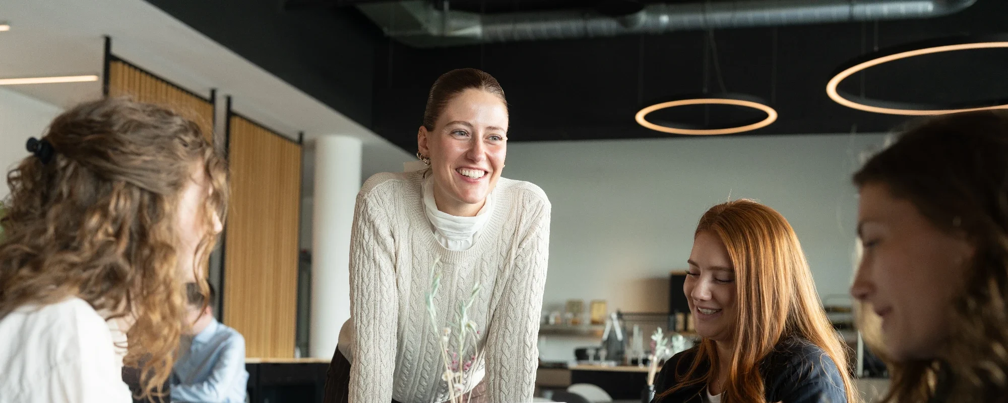 Die ThesisKompass Coachin betreut drei Studierende, sie sitzen an einem Tisch und besprechen sich
